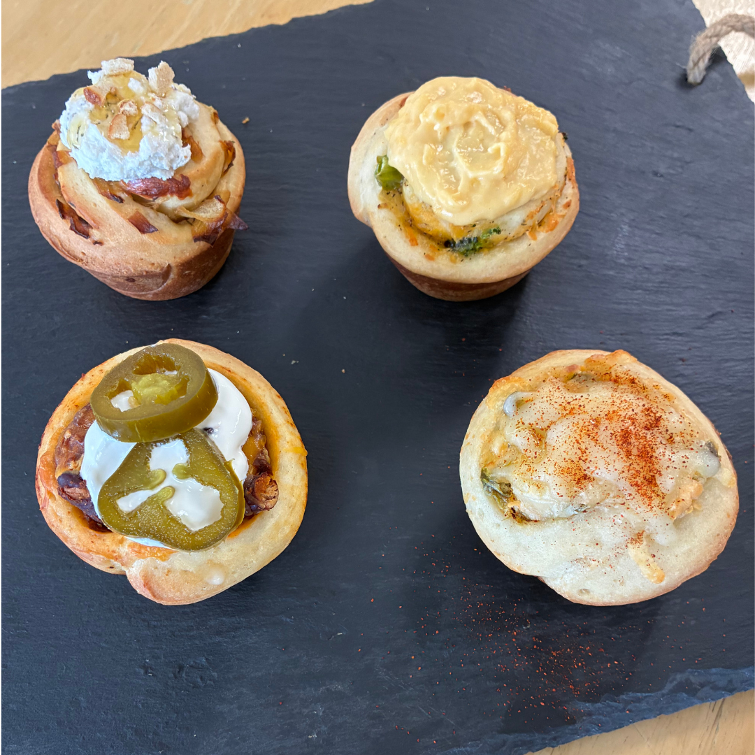 Four savory winter specialty buns made from scratch on a slate board – French Onion with whipped goat cheese, Broccoli Cheddar, Jalapeño Popper, and Chili Cheese – Culinary by Hobby Hill cooking class in Powhatan, VA