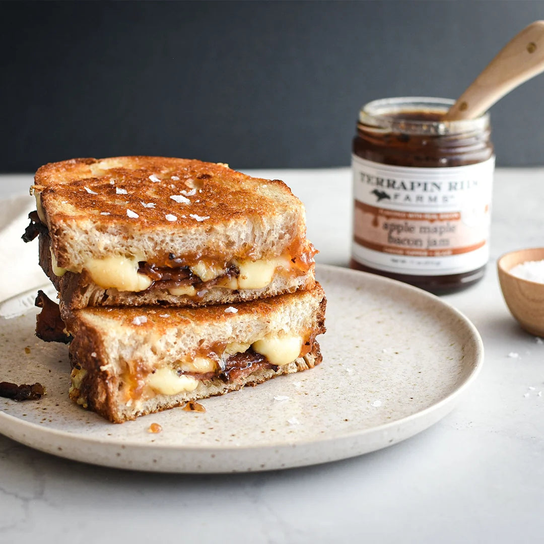 Grilled cheese sandwich on a plate with a jar of Terrapin Ridge Farms Apple Maple Bacon Jam